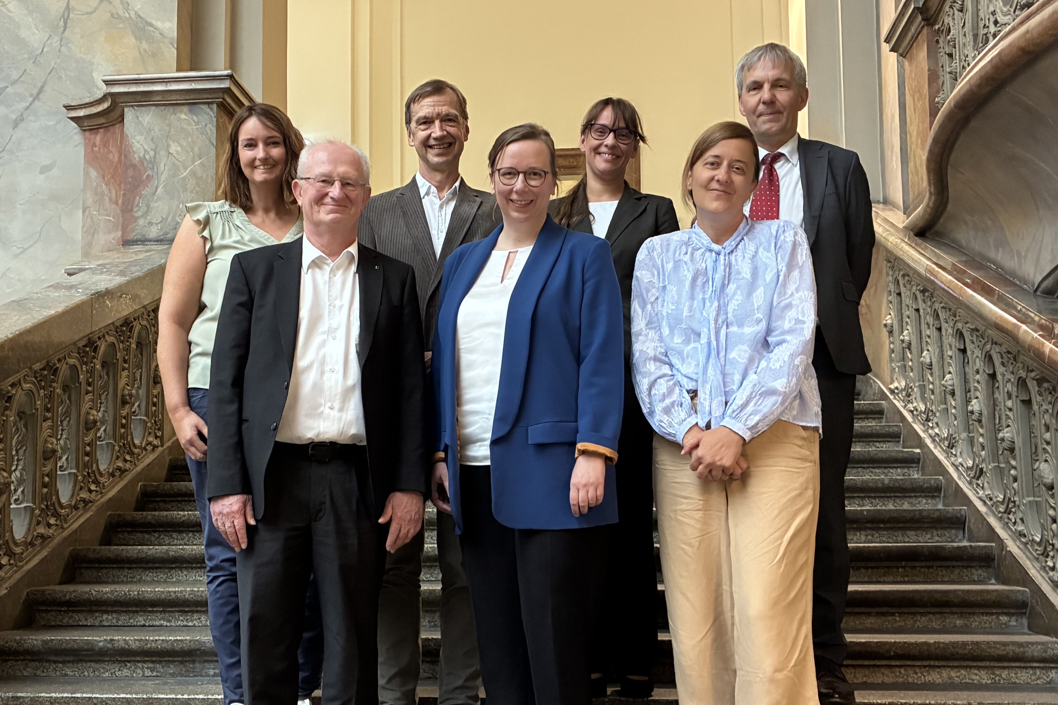 Vier Frauen und drei Männer stehen auf einer Treppe.